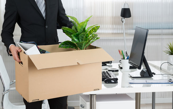 Man with box cleaning out desk